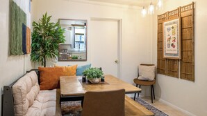 A dining area with a wooden table, chairs, a sofa, and a potted plant. - 1945 Adobe in the Heart of Tucson (Tucson)