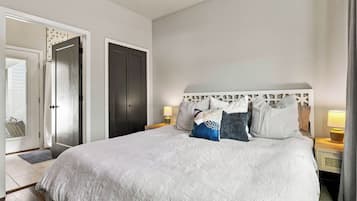 Un dormitorio con una cama grande, un armario y una mesita de noche con lámpara.