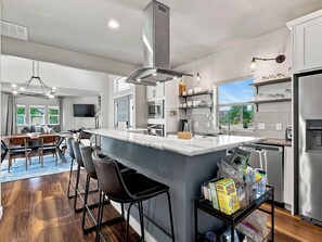 Cozinha moderna com uma ilha grande, eletrodomésticos de aço inoxidável e vista para o exterior.