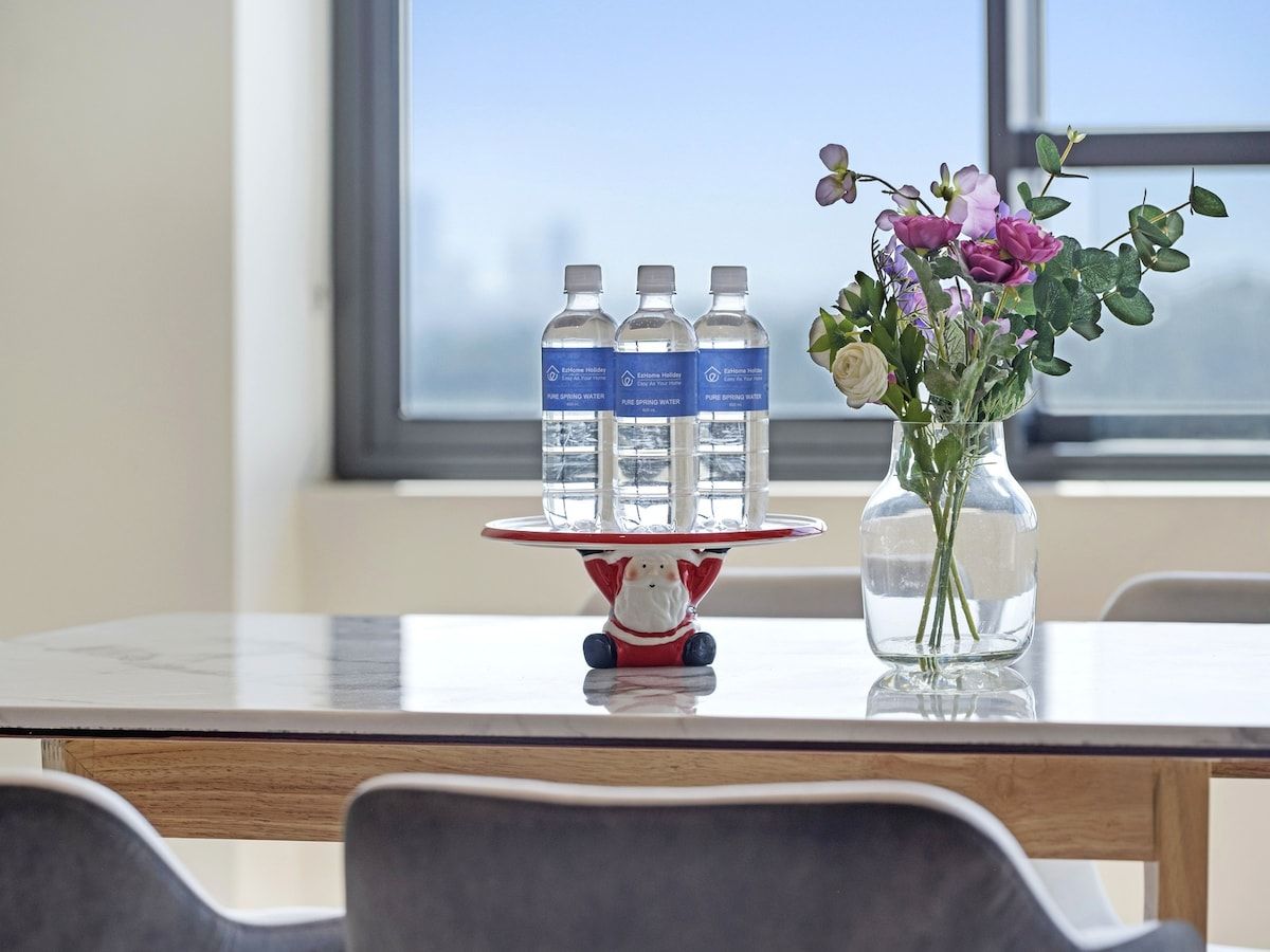 A table with three water bottles labeled 'Ecolab Holiday' and a vase with flowers.