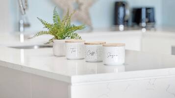 A kitchen counter with three white ceramic containers with wooden lids, each labeled with a different type of tea.