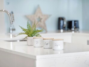 A kitchen counter with three white ceramic containers with wooden lids, each labeled with a different type of tea. - High-Rise 2BR Retreat with Water Views (Wentworth Point)