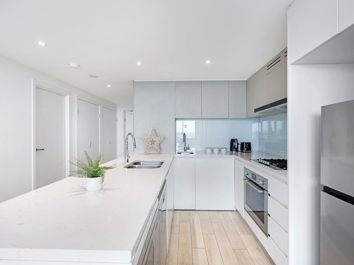 A modern kitchen with white cabinetry, a central island, and stainless steel appliances.