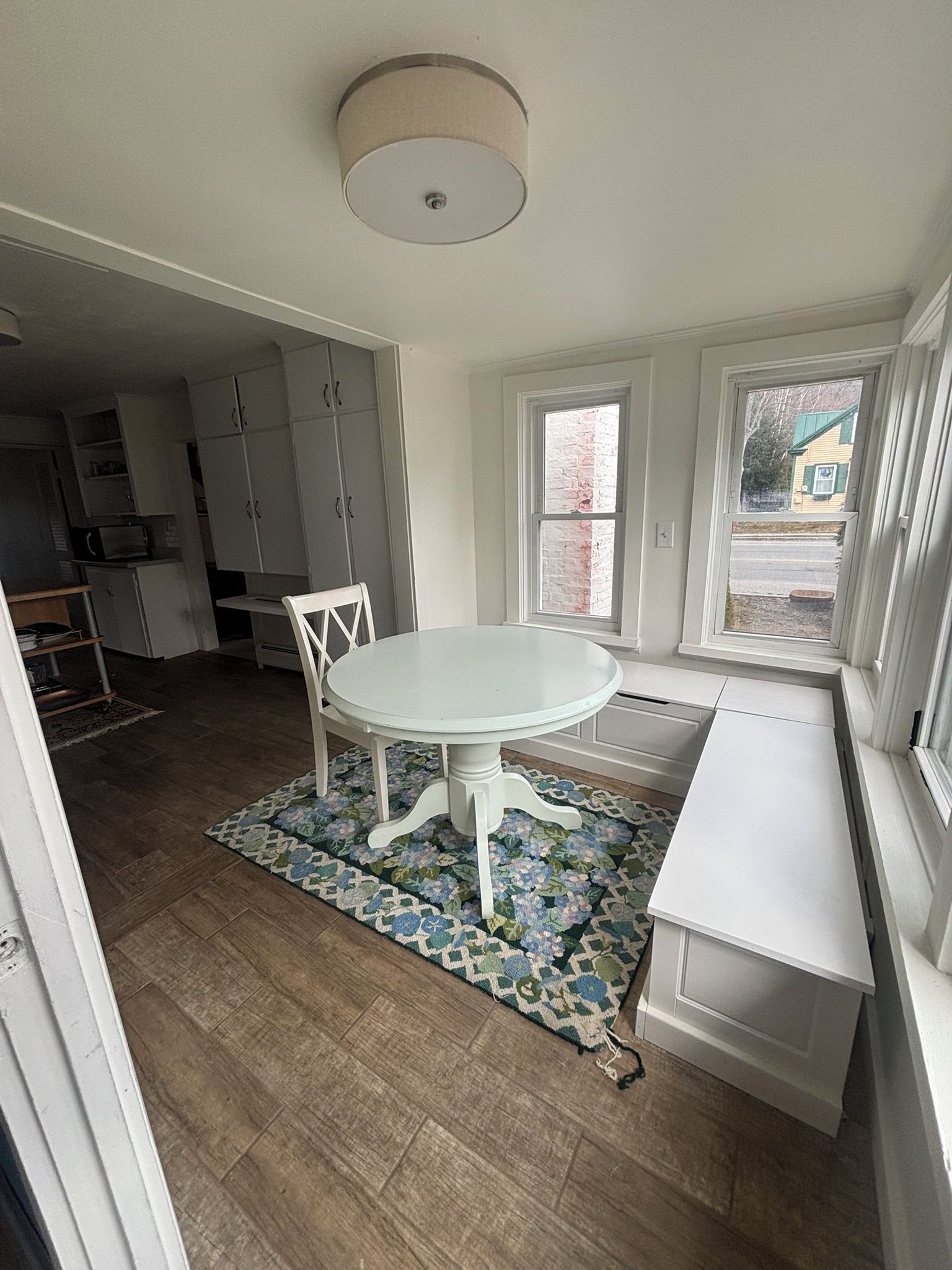 A kitchen with white cabinets, a round dining table, and a patterned rug.