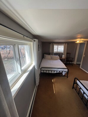 Ein Schlafzimmer mit einem Einzelbett, einem Fenster, einem Stuhl und einem kleinen Tisch.