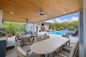 Une terrasse extérieure avec une piscine, des meubles en bois et un espace salon abrité.