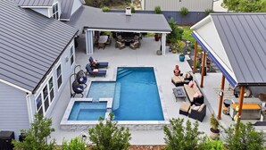Un giardino privato con piscina, area salotto all'aperto e portico coperto.