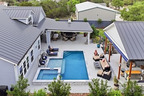 Un jardin à l’arrière d’une maison, avec une piscine, un espace salon extérieur et une terrasse couverte.