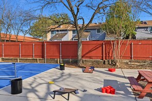 A backyard with a blue tennis court, a picnic table, and a red fence. - Austin Fun House Huge Private Yard, Pickleball, Cowboy Pool & Hot Tub (Austin)