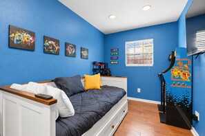 A bedroom with a bed, a dresser, a window with blinds, and wall art. - Austin Fun House Huge Private Yard, Pickleball, Cowboy Pool & Hot Tub (Austin)