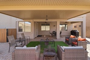 An outdoor patio with wicker furniture, a grill, and a ceiling fan. - Furnished 5BR Home | Office | 30+ Nights (Surprise)