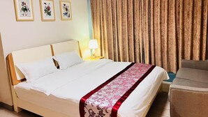 A hotel room with a bed, a nightstand with a lamp, a chair, and three framed botanical prints on the wall. - One Uptown Residence BGC
Sky-High BGC Stay | Work & Relax (Makati City)