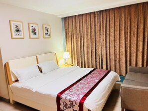 Ein Hotelzimmer mit einem Bett, einem Nachttisch mit Lampe, einem Sessel und drei gerahmten Pflanzenbildern an der Wand.