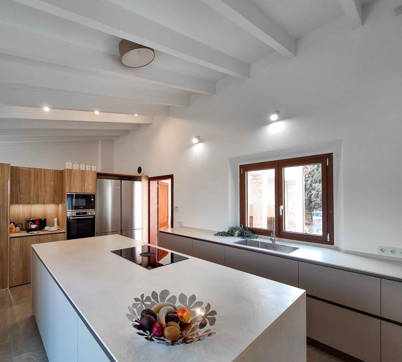Una cocina moderna con una isla central, electrodomésticos integrados y un ventanal que proporciona luz natural.