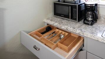 Una cocina con un organizador de cajones que contiene utensilios, un microondas y una cafetera.