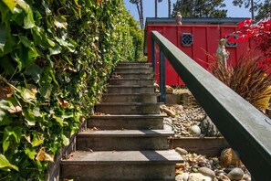 Eine Treppe aus Beton führt zu einem roten Gebäude mit einem schwarzen Geländer.