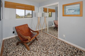 Ein Zimmer mit einem Holzbett, einer Stehlampe, einem großen Spiegel und einem gerahmten Bild an der Wand.