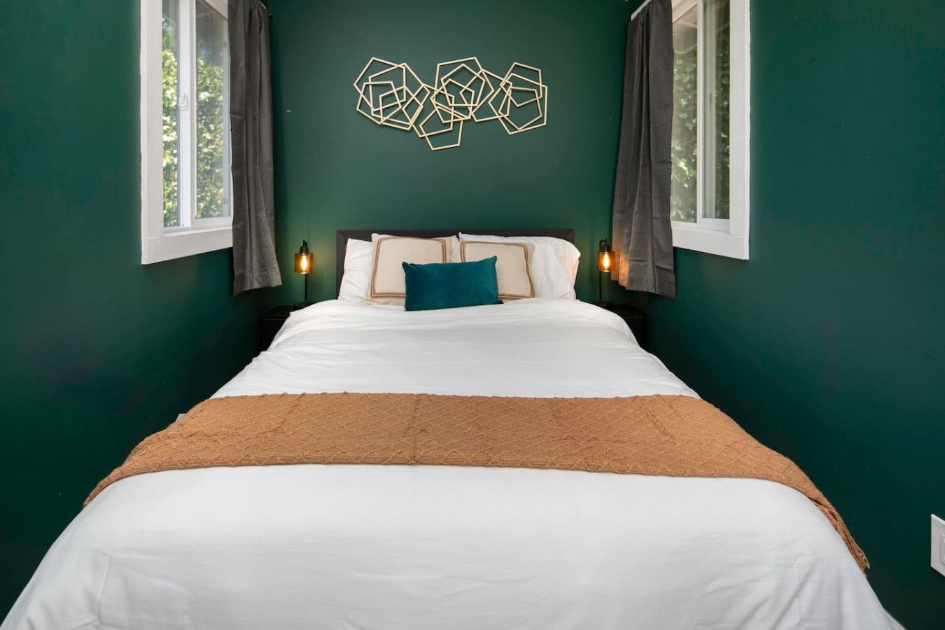 Une chambre avec un grand lit, une œuvre d’art géométrique accrochée au mur et deux lampes de chevet.