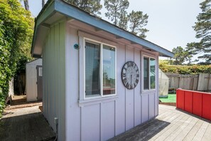 Ein kleines, eingeschossiges Gebäude mit einer Uhr an der Wand, einem Fenster und einer Tür.