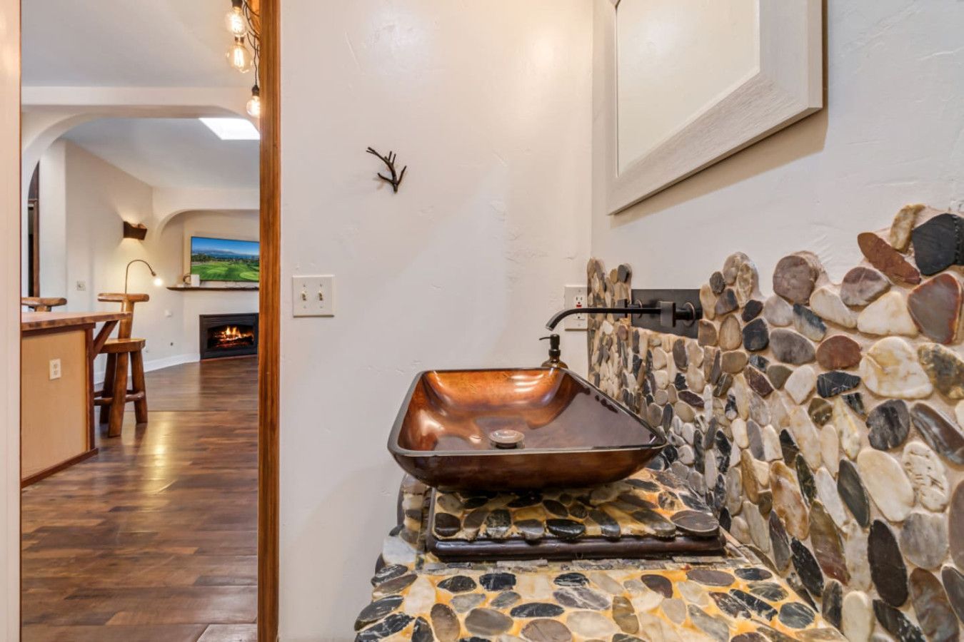 Un baño con lavamanos de cobre, salpicadero de mosaico de piedra y banco de madera.