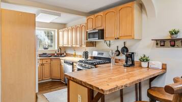 A kitchen with wooden cabinets, a central island, a stove, and a microwave.