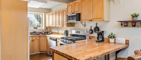 Una cocina con armarios de madera, una isla central, estufa y microondas.