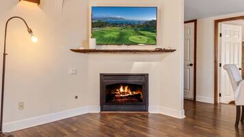 A living room with a fireplace, a mounted television, and a floor lamp.