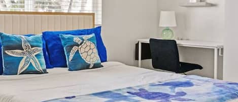 A bedroom with a bed, a desk, and a chair.