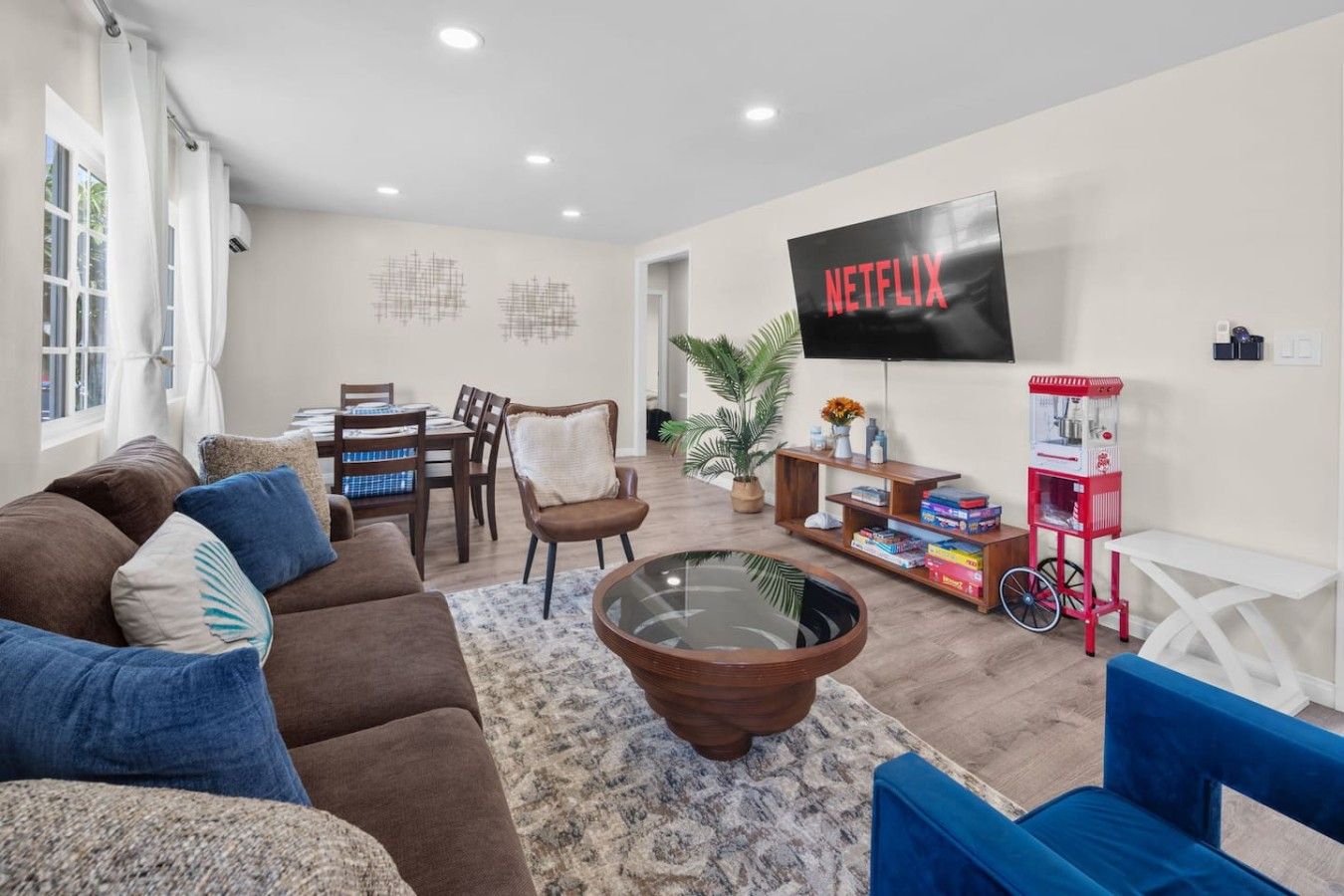 A living room with a sofa, armchairs, a coffee table, a TV, a bookshelf, and a popcorn machine.