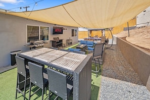 An outdoor patio area with a table and chairs, a barbecue grill, and a Netflix sign. - Bay Park Retreat | 4BR Near Beaches (San Diego)