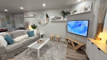 Ein modernes Wohnzimmer mit Sofa, Couchtisch, Fernseher und Dekorationselementen.