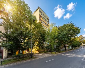 Ein mehrstöckiges Gebäude mit Balkonen, einem wolkenlosen Himmel und Bäumen an der Straße.