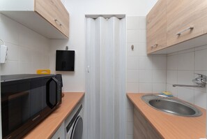 Eine kleine Küche mit Mikrowelle, Backofen und Spüle.