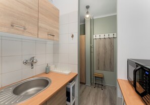 Eine moderne Küche mit Spüle aus Edelstahl, Holzschränken und einer Mikrowelle.