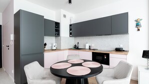 A modern kitchen with a round dining table, two chairs, and a microwave. - Manufaktura Signature Studio (Łódź)