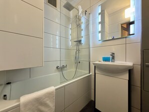 A modern bathroom with a glass-enclosed shower, a white bathtub, and a sink with a mirror above it. - Kościuszki Central Apartment #7 (Wrocław)