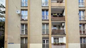 Un edificio residenziale a più piani con balconi, antenna parabolica e un numero civico ben visibile.
