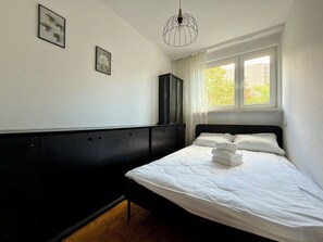 Ein Schlafzimmer mit einem Bett, einem Kleiderschrank und einem Fenster mit Vorhängen.