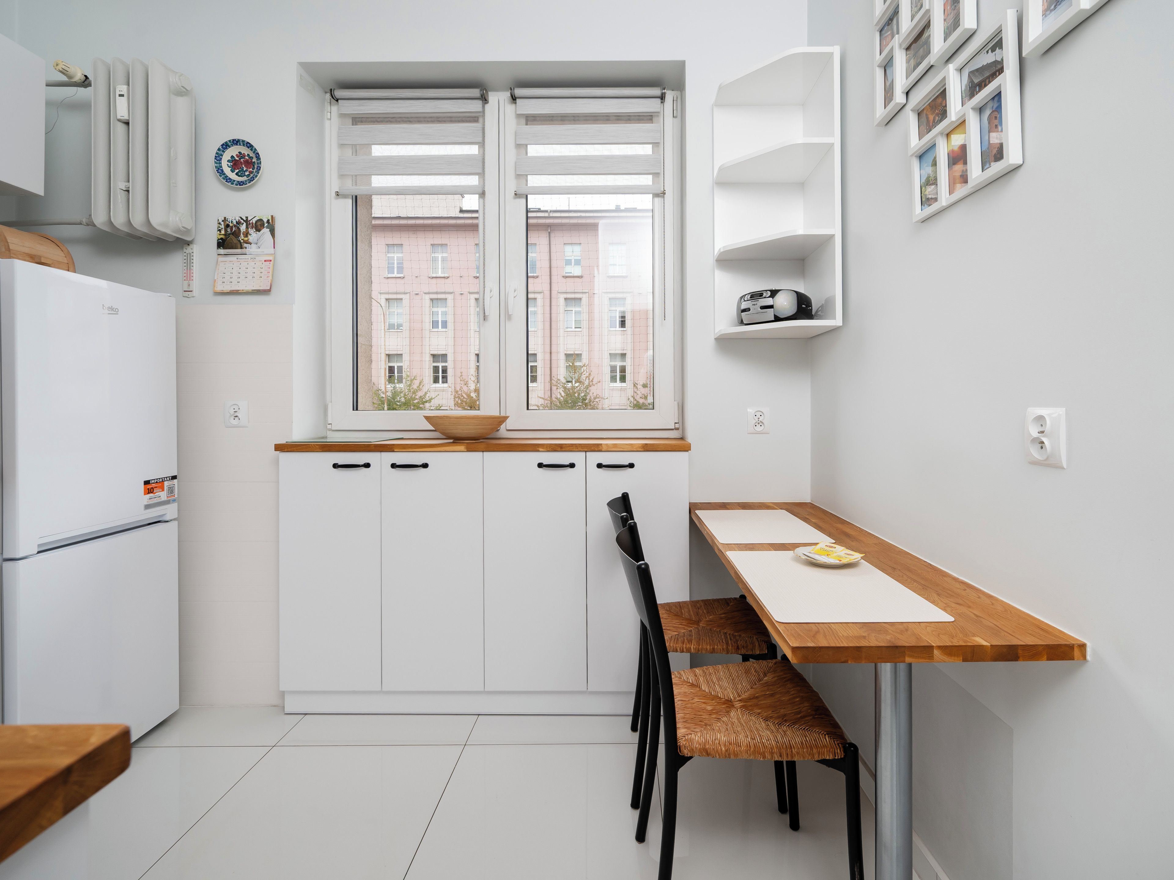 Eine moderne Küche mit weißen Schränken, einer Holz Arbeitsplatte, einem eingebauten Ofen und einem Fenster mit Blick auf Gebäude.