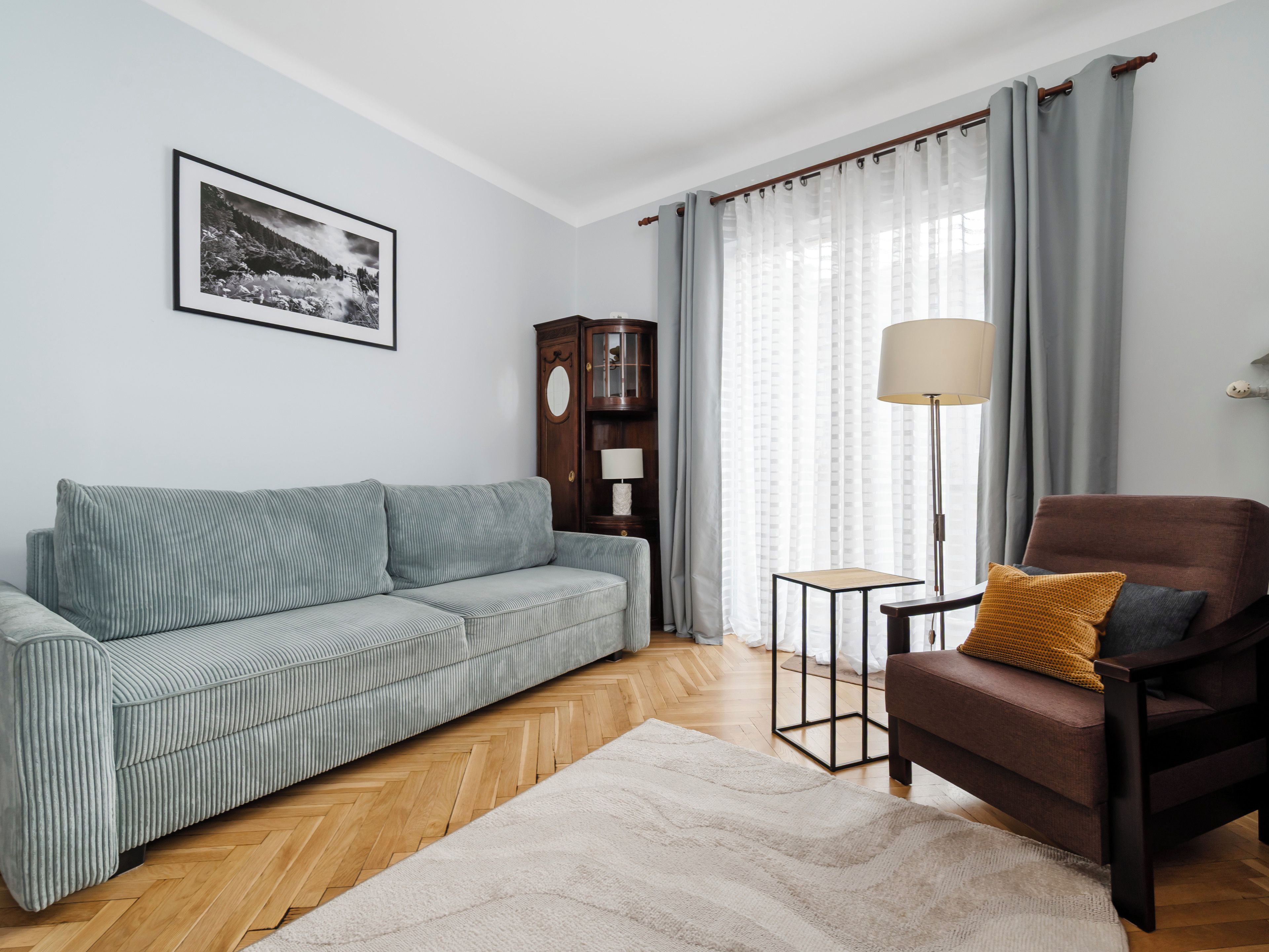 Un salon comprenant un canapé, un fauteuil, une lampe et un meuble.