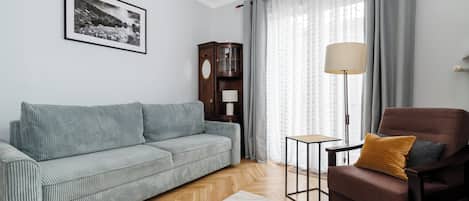 A living room with a sofa, armchair, lamp, and a cabinet.