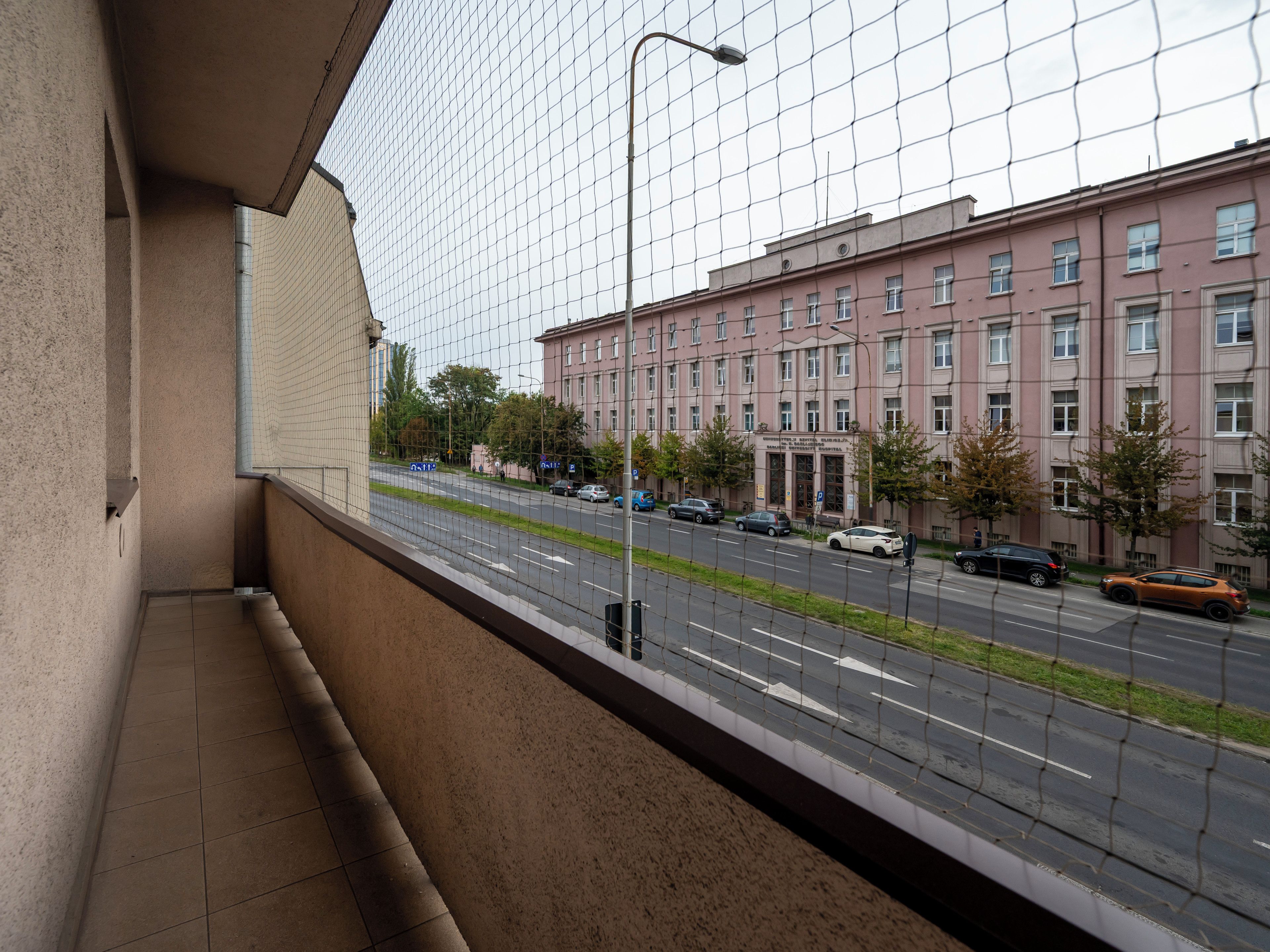 Ein Balkon mit Blick auf eine Straße und ein Gebäude mit vielen Fenstern.