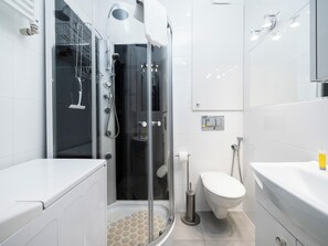 Et stilfuldt badeværelse med et glasvæg-afskærmet brusebad, toilet og vask.
