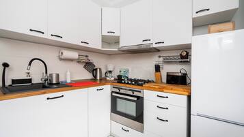 Een moderne keuken met witte kasten, een roestvrijstalen fornuis en een inbouwoven.