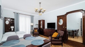 A hotel room with a bed, a dining table with placemats, a television, a cabinet, and a mirror. - Kopcińskiego Cozy City Studio (Łódź)