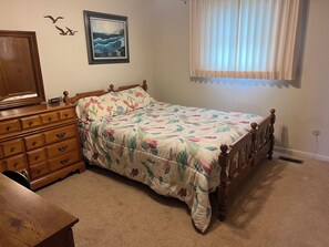 Quarto com cama, penteadeira e um quadro na parede.