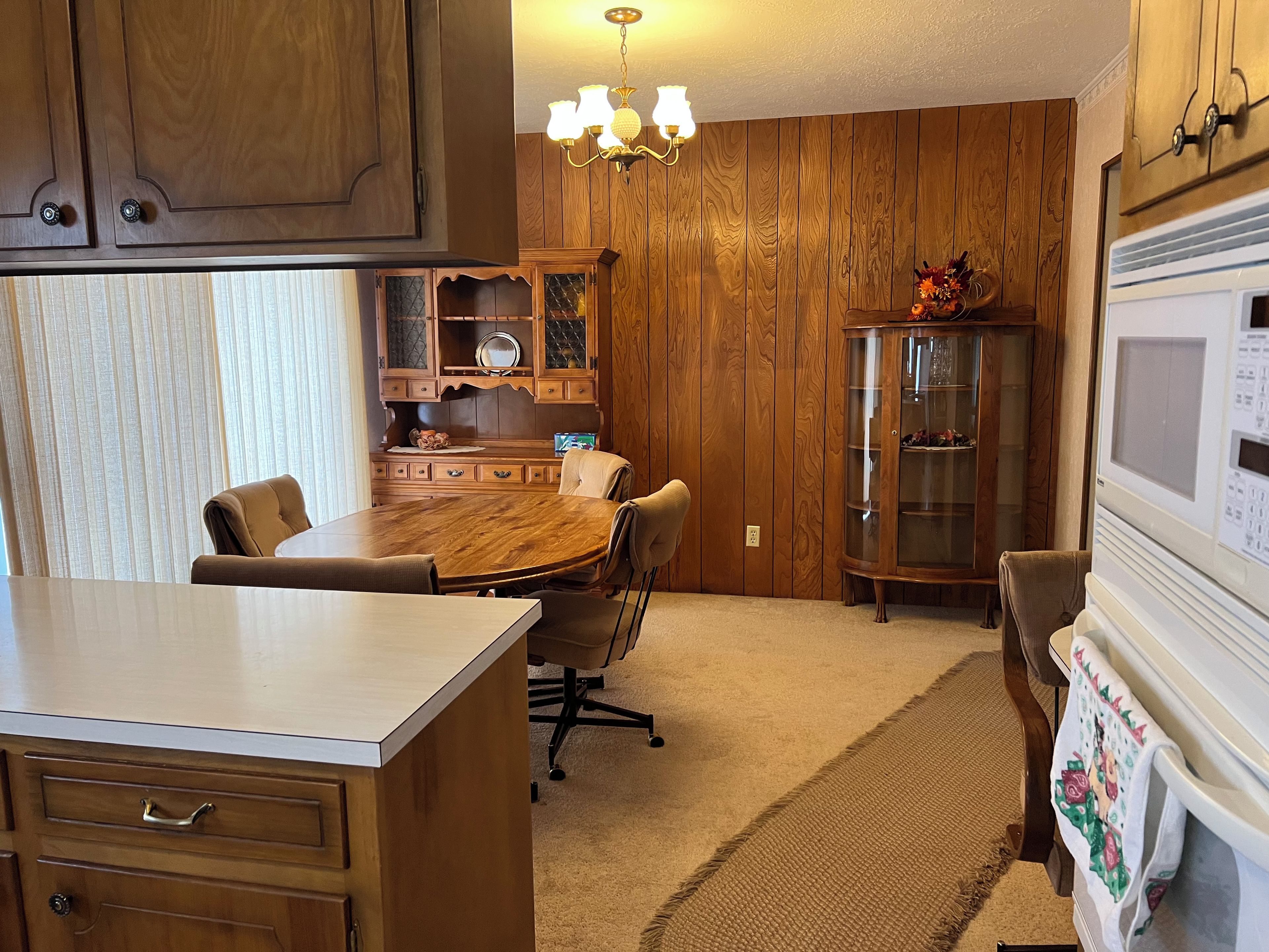 A wooden-paneled kitchen with a dining table, chairs, and a built-in microwave.