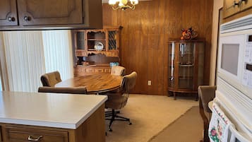 A wooden-paneled kitchen with a dining table, chairs, and a built-in microwave.