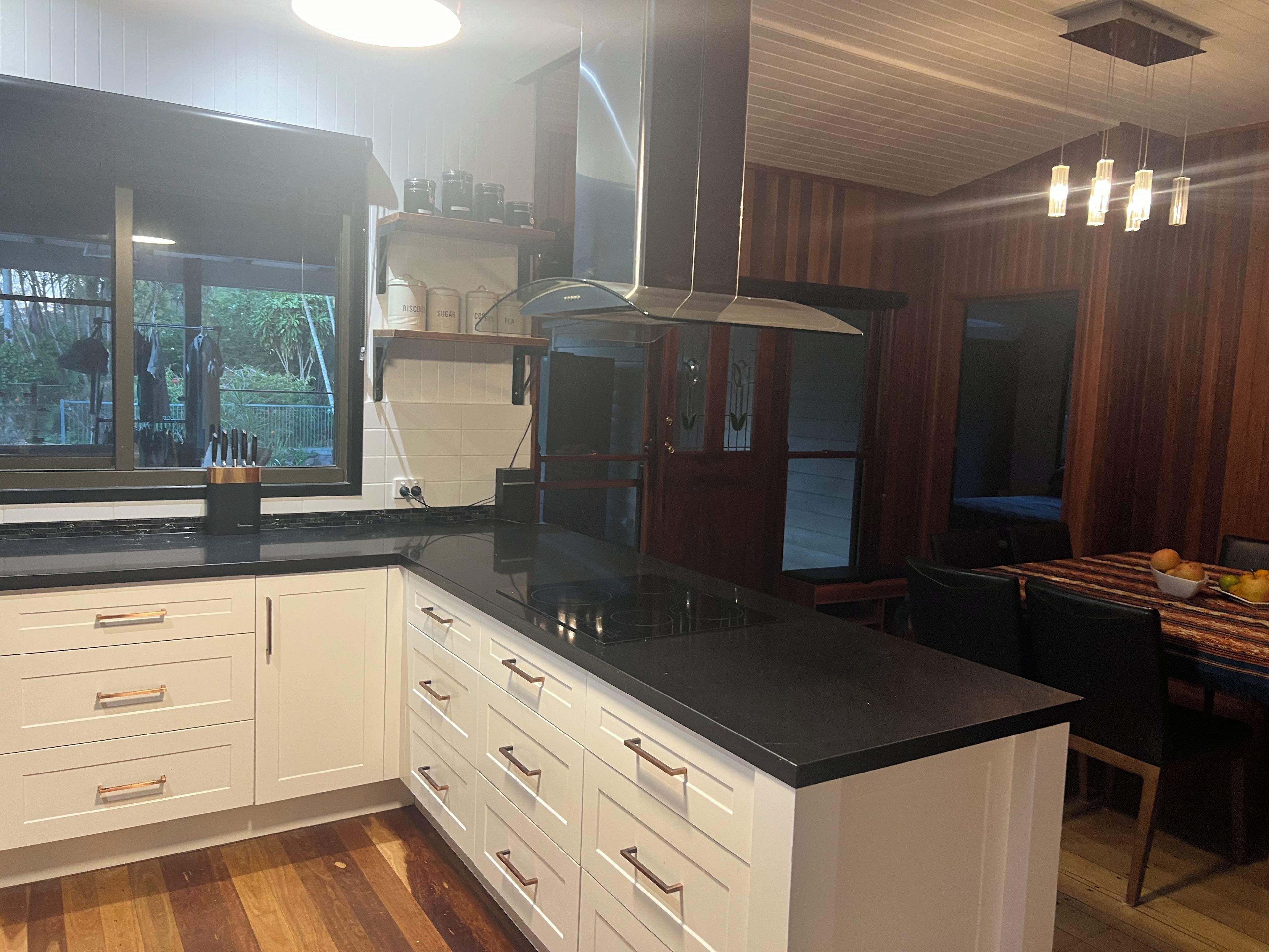 A modern kitchen with white cabinetry, a black countertop, and a built-in stove.