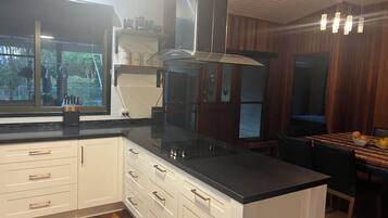 A modern kitchen with white cabinetry, a black countertop, and a built-in stove.